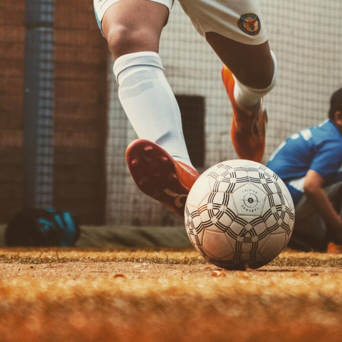 close up on soccer athlete's feet kicking ball